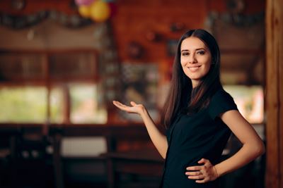 Chica que trabaja en un restaurante recibiendo a los comensales