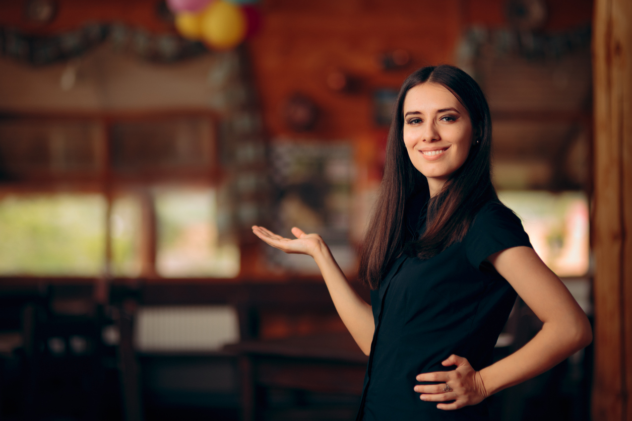 Chica que trabaja en un restaurante recibiendo a los comensales